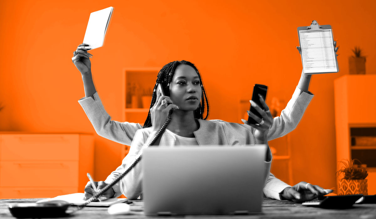 Woman at a desk and laptop juggling multiple tasks, showing employee productivity