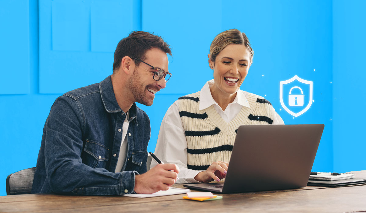 Two employees securely reviewing information on a laptop screen. 